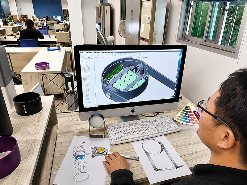 Engineering team reviewing 3D product design and technical drawings for integrated manufacturing support.